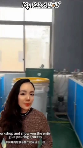 Presenter In A Doll-Production Workshop Beside Moulding Equipment.